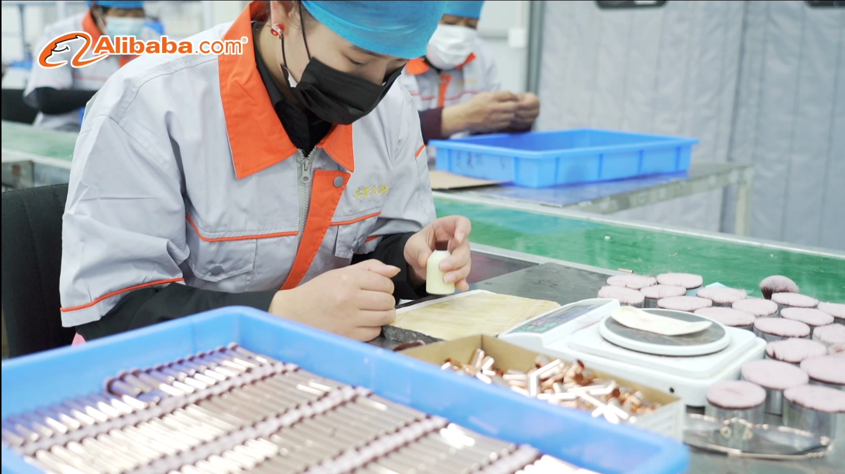 Worker making brush heads by hand beside prepared brush components